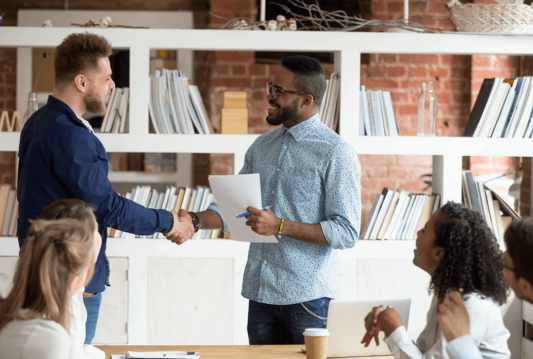 Two employees shaking hands in a meeting