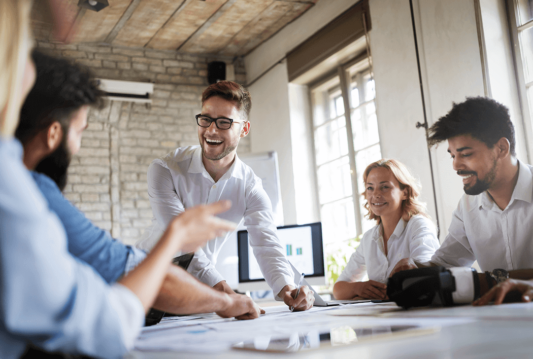 Employees laughing around a board room table