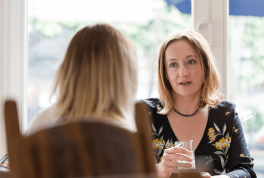 Two women sitting across from one another talking