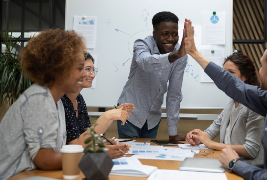 Employees in a meeting high fiving eachother