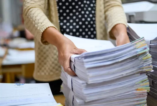 A stack of files with a woman holding the first few files in her hands