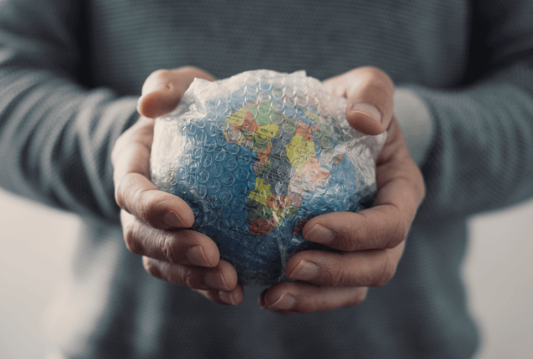 A person holding a globe wrapped in bubble wrap