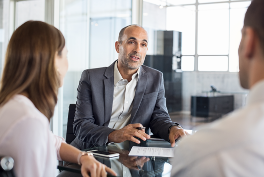 3 people sitting around a desk talking